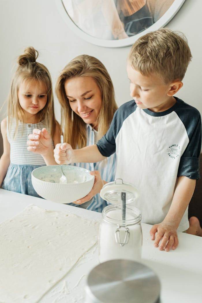 about-us-01 A joyful family moment in the kitchen as a mother and her children mix ingredients.