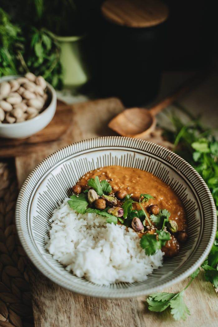 services-02 A bowl of vegan lentil curry with rice garnished with cilantro, perfect for a healthy meal.